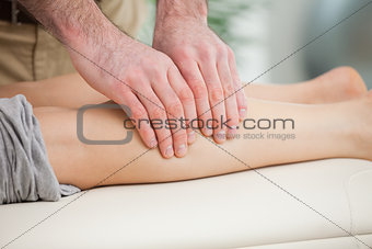 Woman lying forward while a man massaging her calf