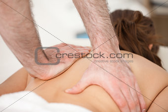 Woman lying on the belly while being massaging with two hands of