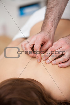 Back of a woman being massaging while fingertips of doctor