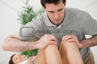 Serious doctor pressing on the knees of a patient