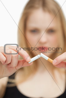 Close up of a blonde-haired woman breaking a cigarette
