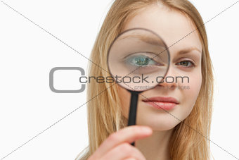 Close up of a woman placing a magnifying glass on her eyes