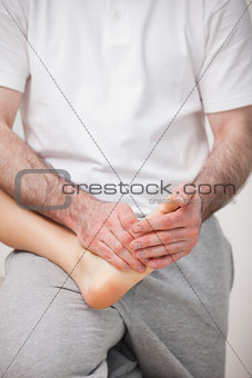Podiatrist manipulating the foot of a woman while holding it on 