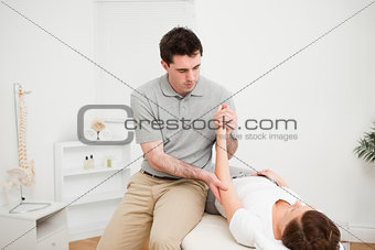 Doctor examining the arm of his patient while touching his elbow