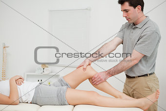 Physiotherapist examining the knee of his patient while touching