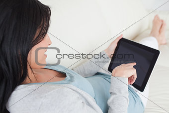 Woman laying on a sofa while holding a tactile tablet