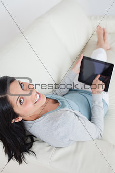 Woman relaxing on a sofa while touching a tablet