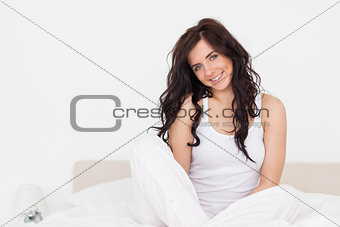 Cheerful brunette woman sitting on her bed