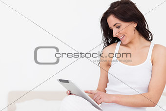 Smiling brunette woman sitting while using her touchscreen
