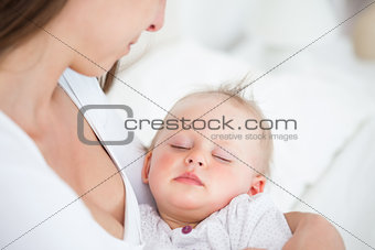 Baby falling asleep in the arms of her mother