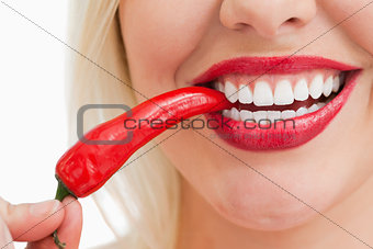 Happy woman eating a red chili