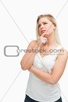 Blonde woman placing her fingers on her chin while crossing her 