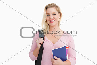 Blonde woman standing while holding notebooks