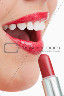 Woman opening her mouth while applying lipstick on her lips