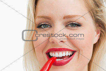 Blonde woman biting a chili