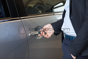 Man opening a car door with a key