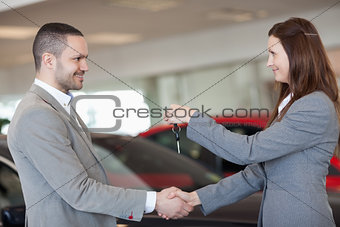 Man receiving car keys while shaking hand