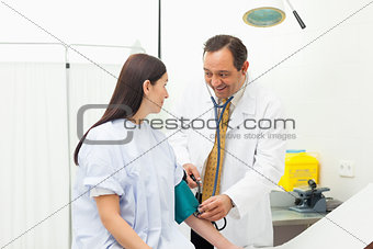 Smiling doctor placing a sphygmomanometer