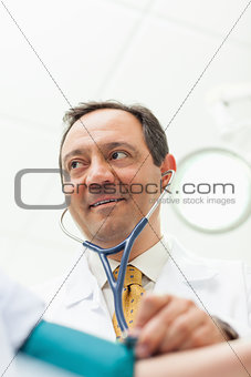 Smiling doctor measuring the blood pressure of his patient