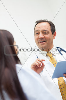 Smiling doctor talking with a patient while holding a tablet
