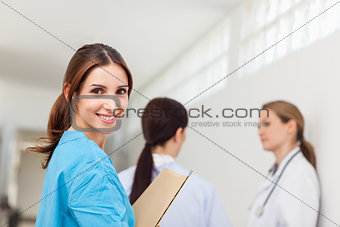 Smiling nurse  while standing in a hallway with a patient and a 