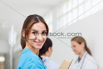 Smiling woman  while standing in a hallway with a patient and a 
