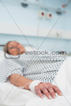 Focus on the hand of a patient lying on a medical bed