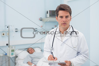 Doctor writing while holding a chart