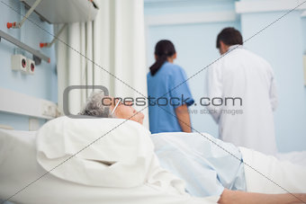 Patient lying on a bed next to a doctor and a nurse