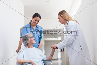 Patient in a wheelchair holding hand of a doctor