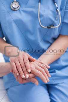 Close up of a nurse holding hand of a patient