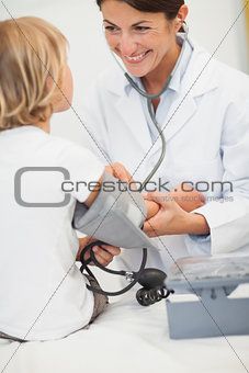 Smiling doctor measuring blood pressure of a child