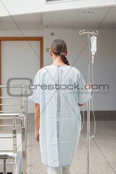 Rear view of a female patient holding a drip stand