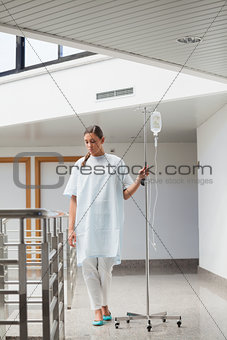 Female patient walking while holding a drip stand