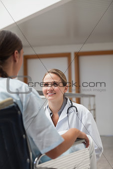 Smiling doctor squatting next to a patient on a wheelchair