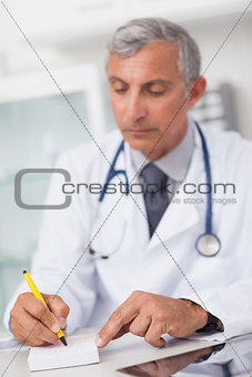 Doctor writing on a notepad at his desk