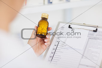 Pharmacist holding a drug bottle and a clipboard