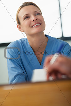 Nurse looking at someone who signing a paper