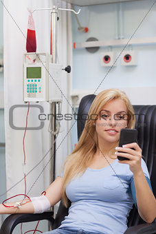 Female blood donor looking at her mobile phone