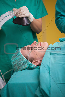 Nurse holding an oxygen mask above the head of patient