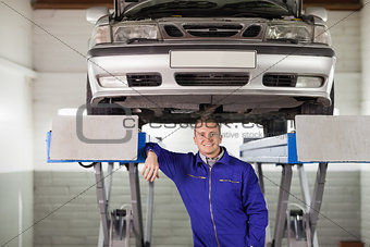 Smiling mechanic below a car