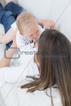 Mother lying on a sofa with a baby on her chest
