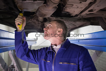 Man looking at the below of a car while repairing