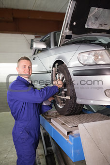 Mechanic standing while repairing a car wheel