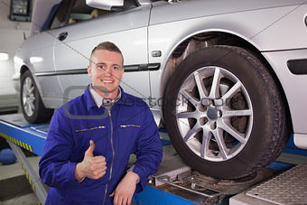 Man looking at camera next to a car with his thumb up