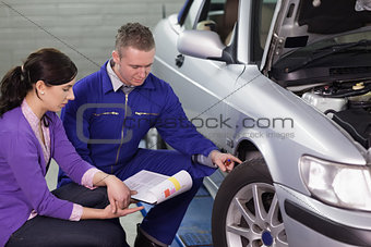 Mechanic showing the car wheel to a woman