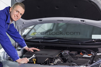 Mechanic leaning on a car looking at camera