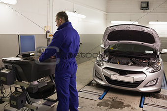 Mechanic looking at a computer while standing