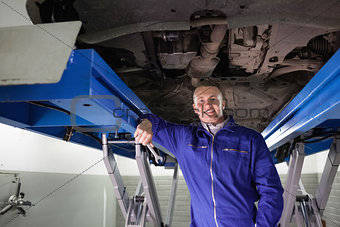 Smiling mechanic leaning on a machine