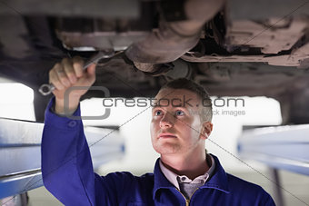 Mechanic repairing a car with a spanner